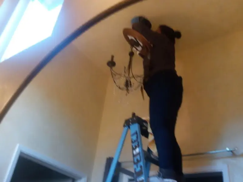 Electrician installing a chandelier in a Mableton residence